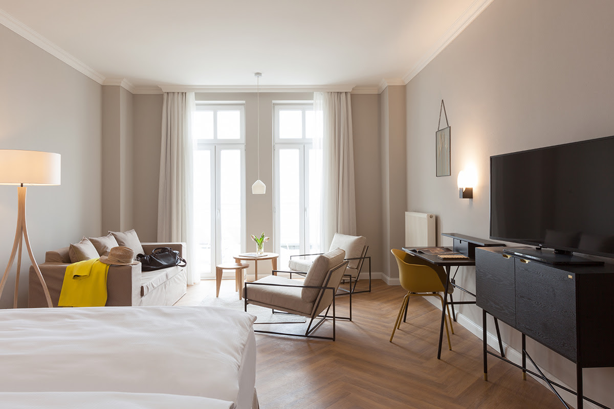 Geräumiges Zimmer im Vju Hotel mit edler Einrichtung, bodentiefen Fenstern und stilvollen Möbeln für höchsten Komfort auf Rügen.