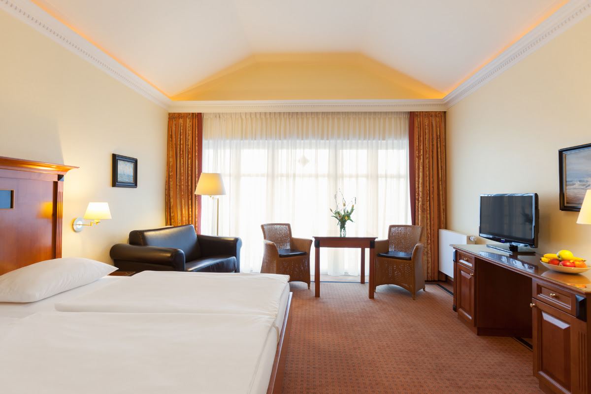 Großes Doppelzimmer mit gemütlichem Bett und warmer Atmosphäre im Vju Hotel auf Rügen mit zahlreichen Urlaubsangeboten.