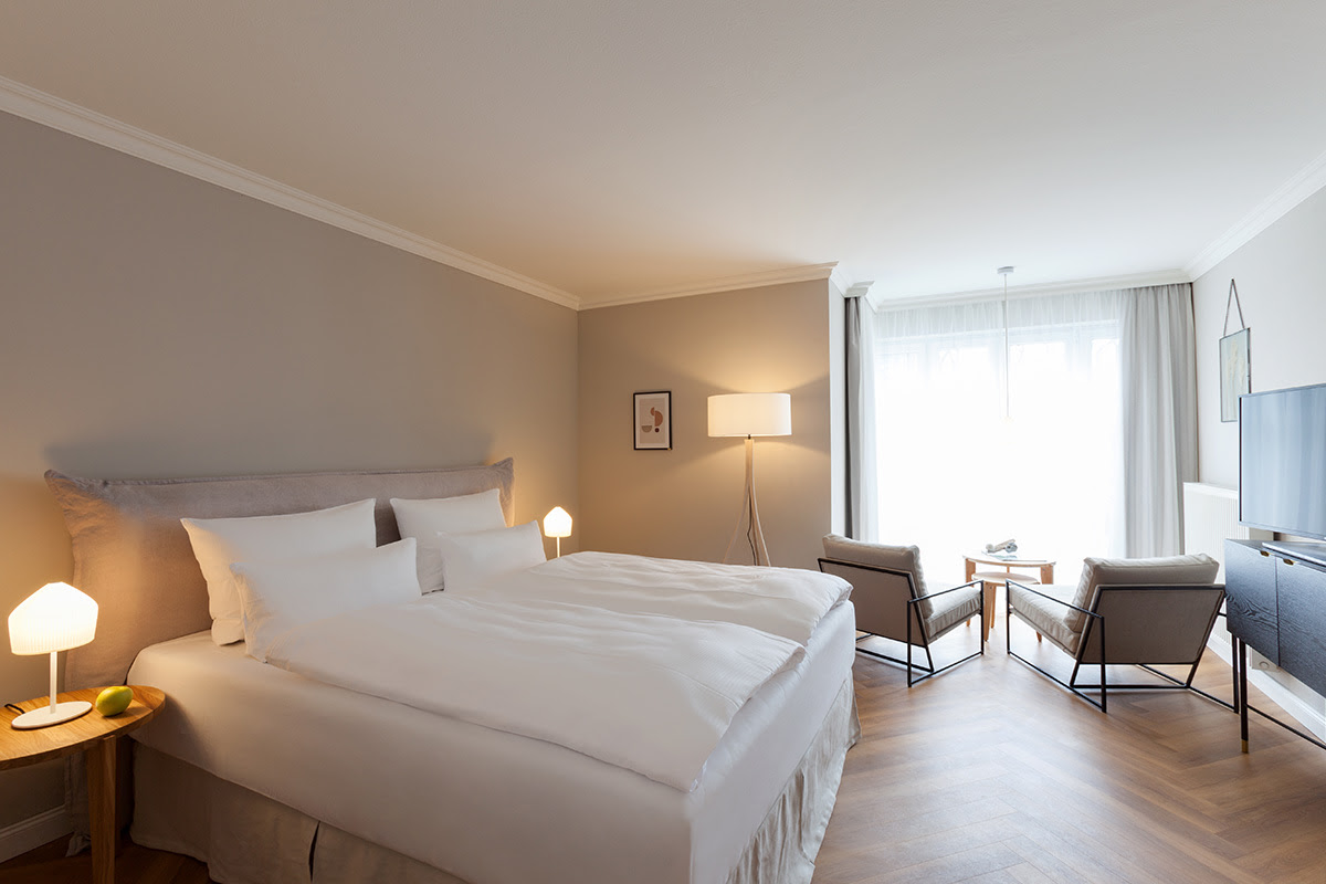 Helles Doppelzimmer mit großem Bett, gemütlichem Wohnbereich und modernen Möbeln im Vju Hotel mit zahlreichen Angeboten.