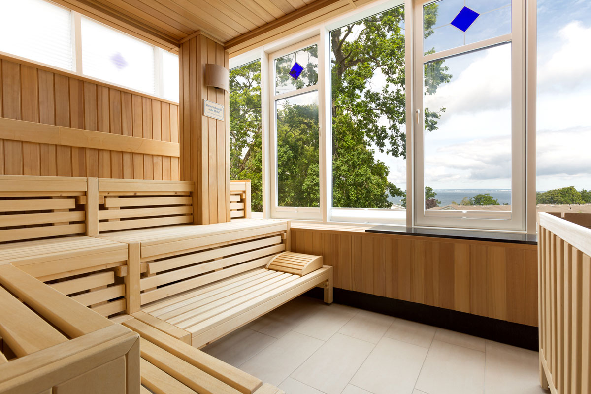 Innenraum der Sauna mit Holzbänken und Panoramafenstern mit Ostseeblick im Vju Hotel auf Rügen mit zahlreichen Angeboten.