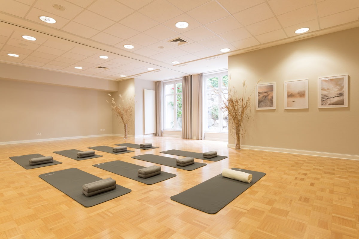 Heller Yoga-Raum im Vju Hotel Rügen mit ausgelegten Matten, Meditationskissen und weichen Handtüchern für entspannende Sessions.