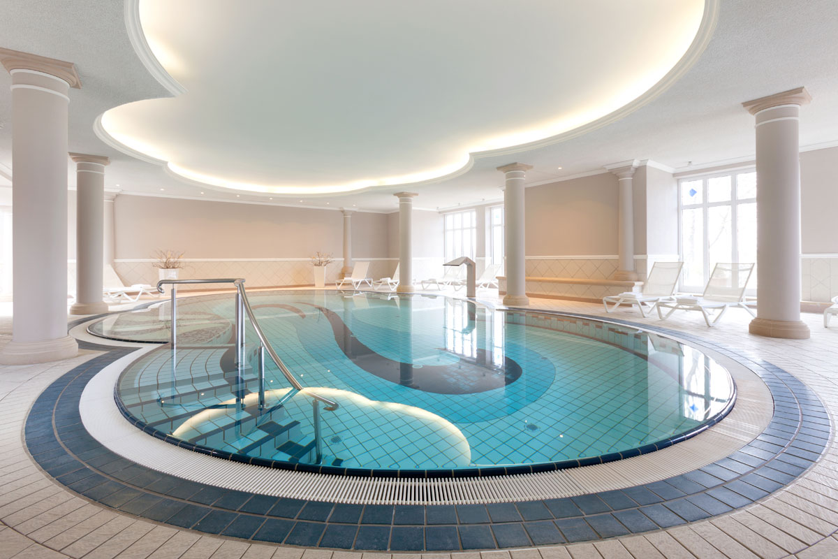 Indoorpool im Vju Hotel mit stilvoller Beleuchtung, gemütlichen Liegen und entspannter Atmosphäre in Ihrem Rügenurlaub.