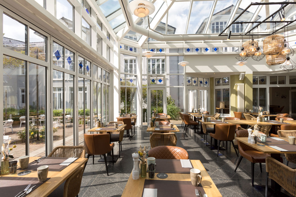 Einladender Wintergarten, Teil des Restaurants im Vju Hotel, mit kulinarischen Angeboten im Urlaub auf Rügen.