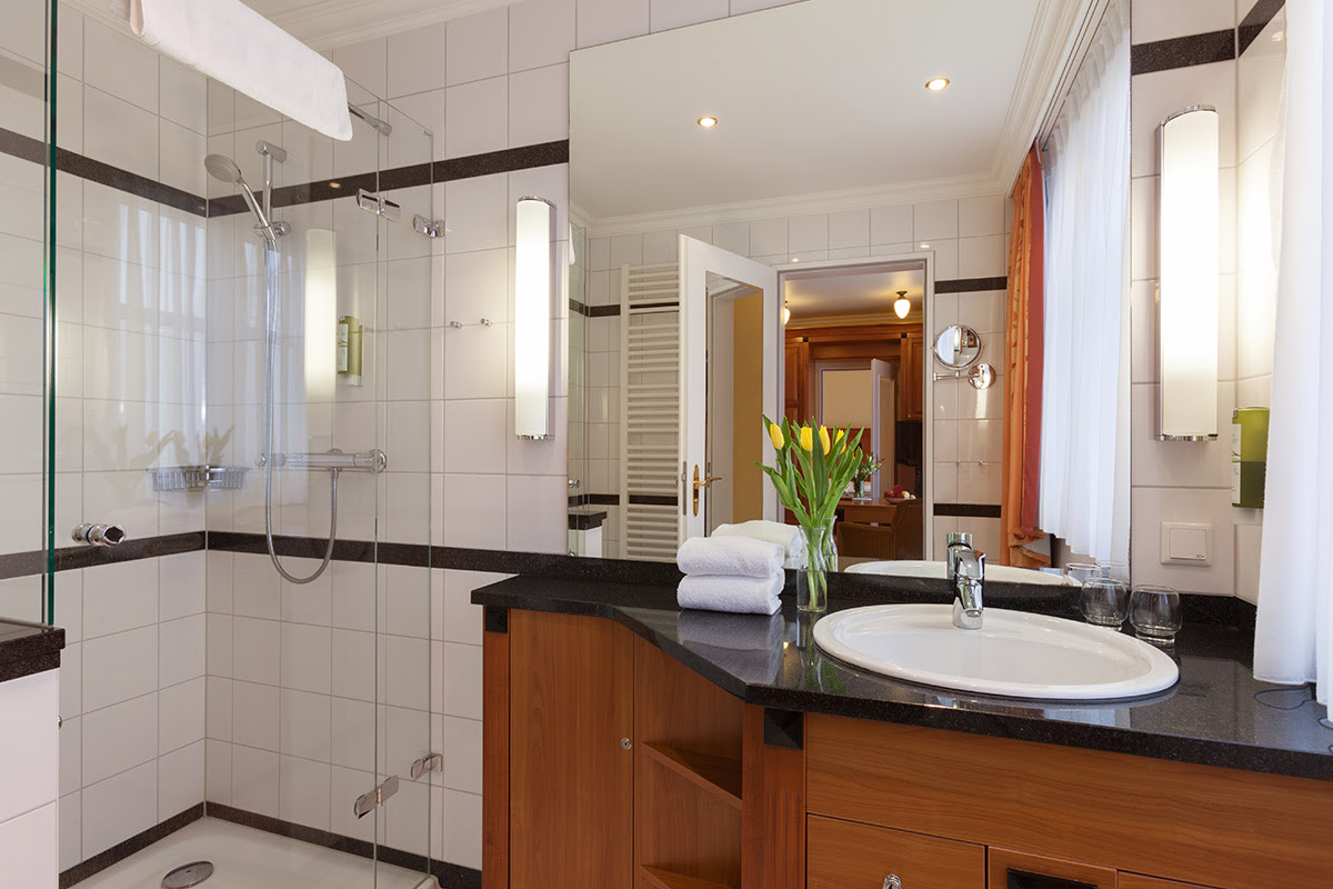 Modernes Bad mit geräumiger Dusche, stilvollem Waschtisch und großem Spiegel im 2-Raum-Zimmer im Vju Hotel auf Rügen.
