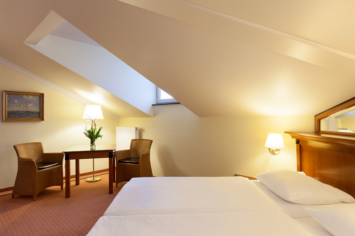 Komfortables Hotelzimmer in den Dependancen des Vju Hotels mit gemütlichem Doppelbett, Dachfenster und Sitzbereich.