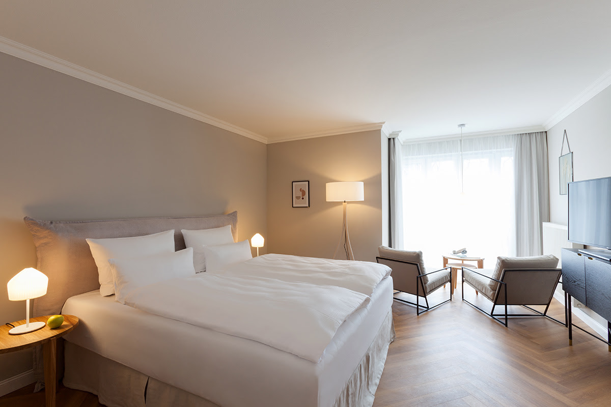 Helles Doppelzimmer mit komfortablem Bett, Leseecke und Schreibtisch im Vju Hotel auf Rügen.