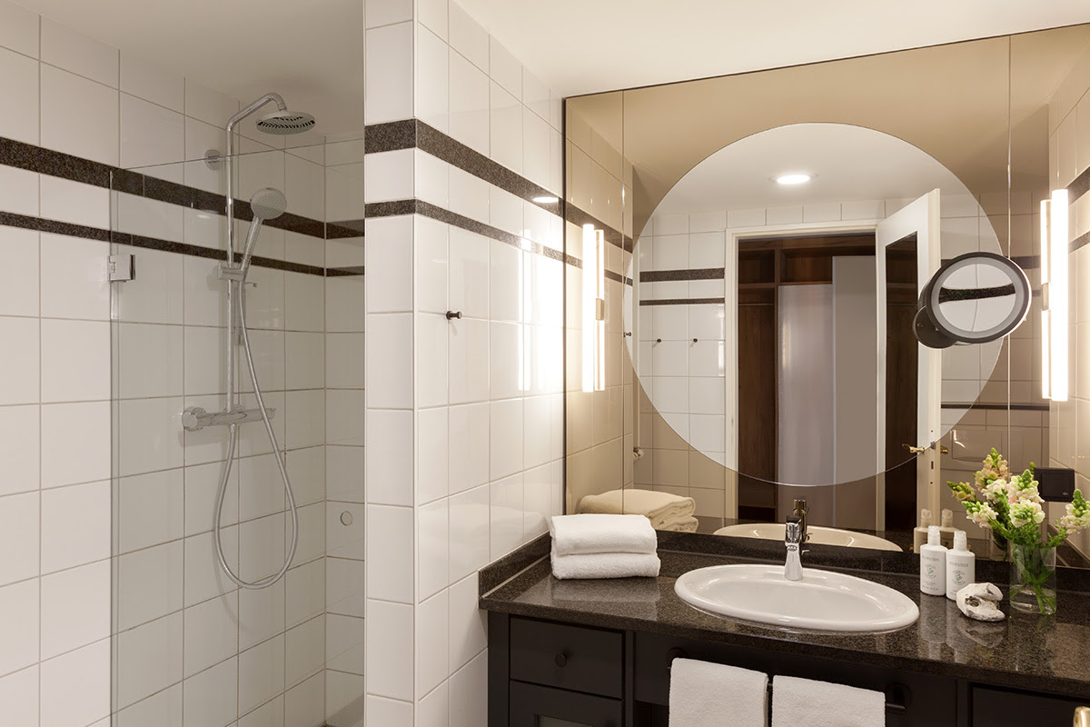 Helles Hotelbad mit großer Dusche, Spiegel und modernen Akzenten im Doppelzimmer mit Ostseeblick des Vju Hotels.