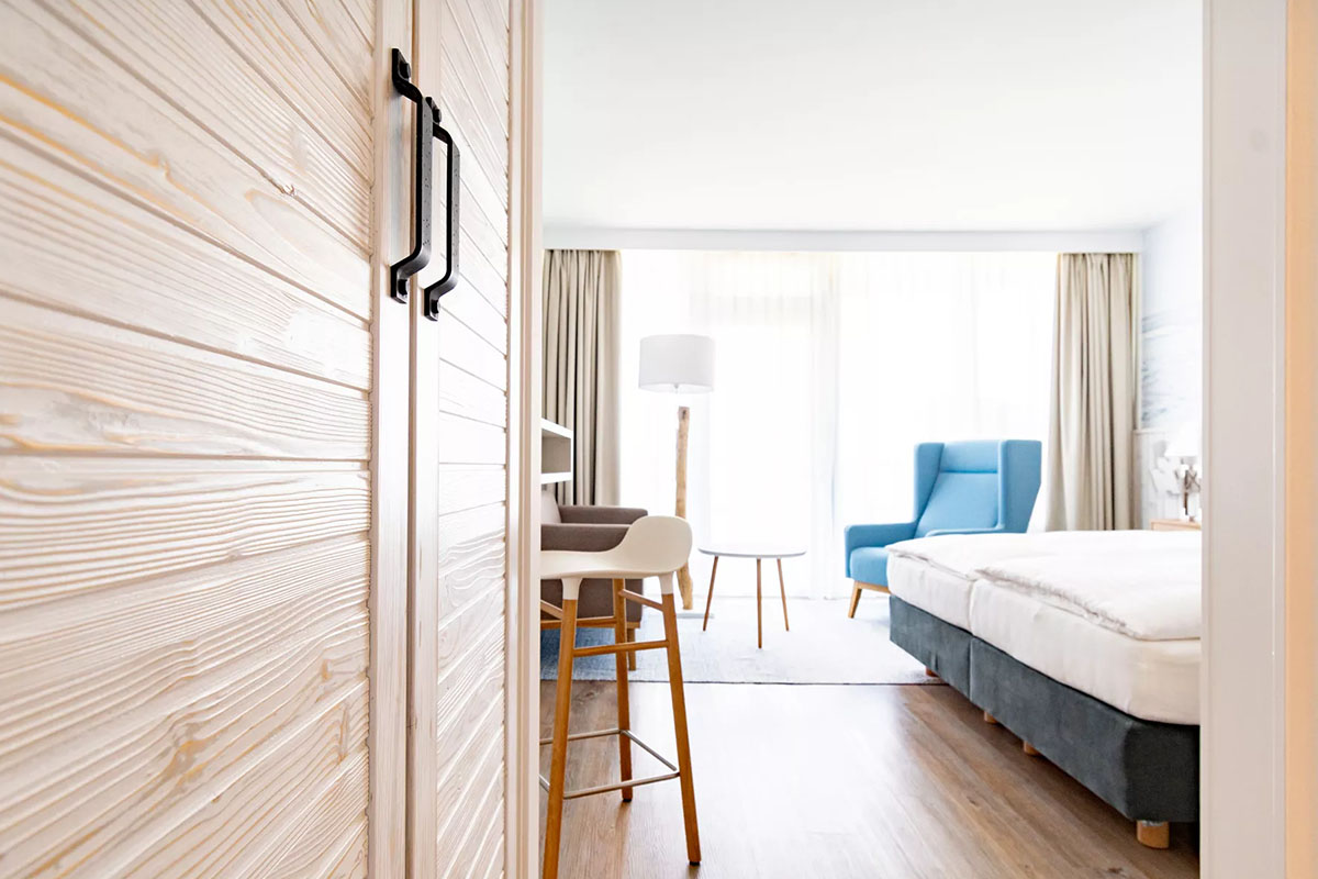 Eingangsbereich des Zimmers Buhne im Wyn. Strandhotel mit Naturholz-Schrank und warmem Licht.