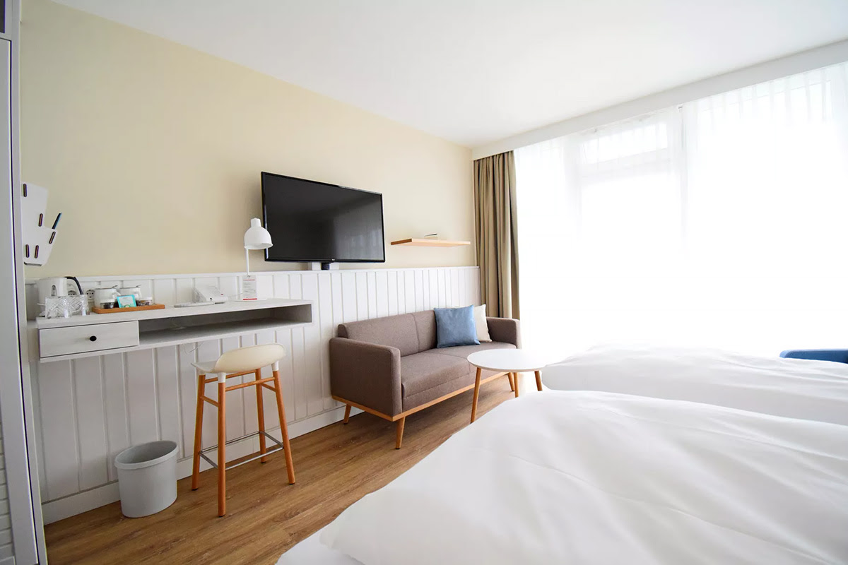 Stilvoll eingerichtetes Zimmer Buhne im Wyn. Strandhotel mit Schreibtisch, Sitzbereich und bodentiefen Fenstern.