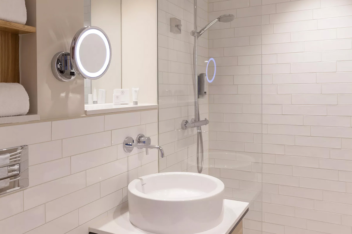 Helles Hotelbad mit großer Dusche, Kosmetikspiegel im Muschelsucher-Zimmer des Wyn. Strandhotels auf Sylt.